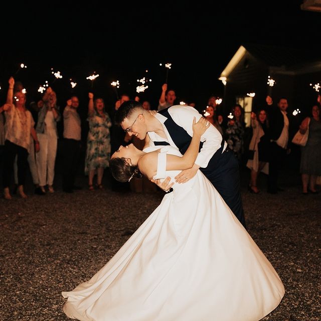guests using sparklers for wedding exit while the groom dips the bride back for a kiss