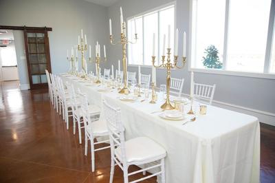 reception hall with white chairs, large windows and gold accent